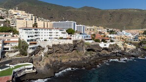 A coastal town with buildings along the cliffside, rocky terrain, and a view of the sea. - Over the Ocean with pool (Candelaria)