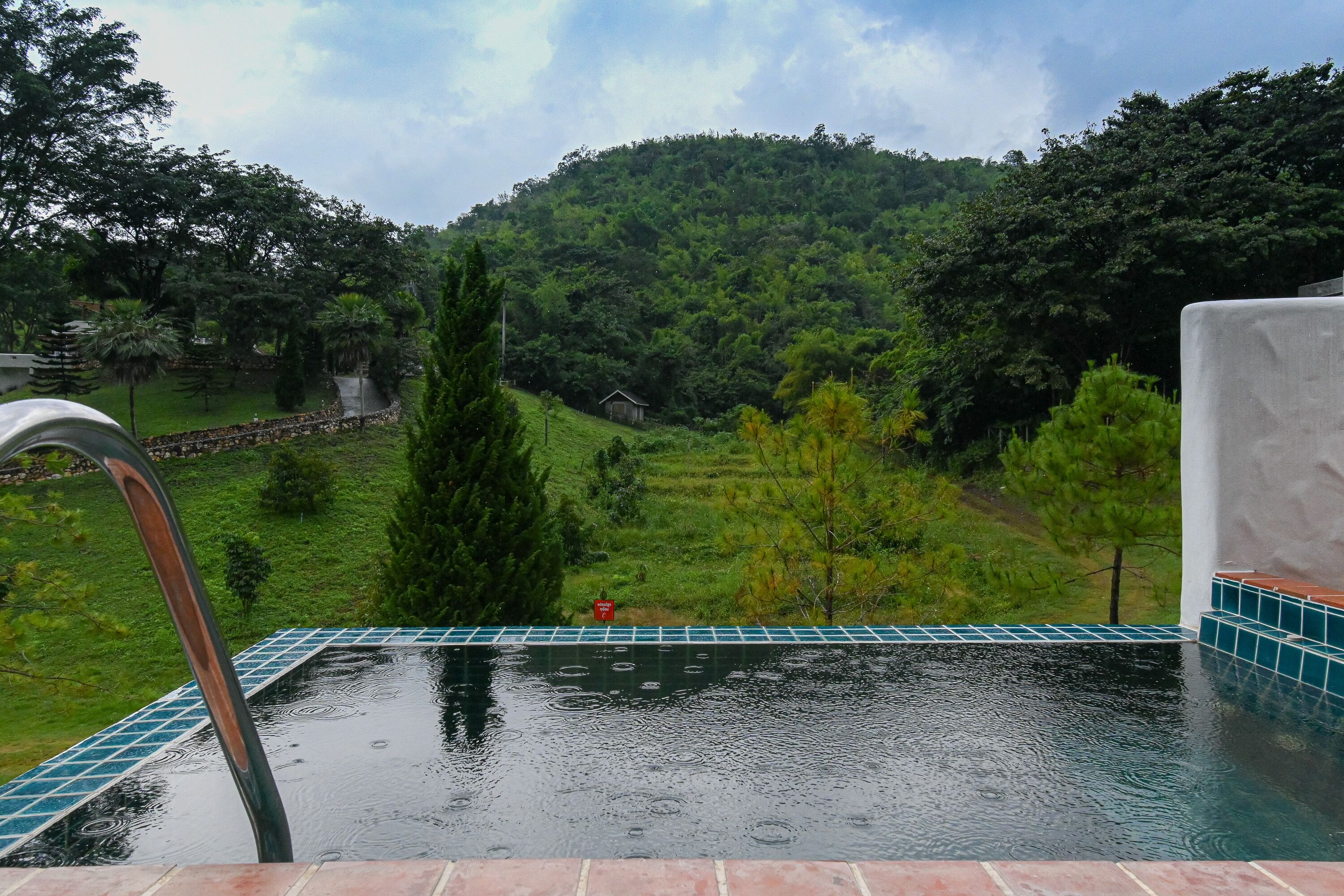 Una piscina amb vista a un paisatge verd i una collada al fons.
