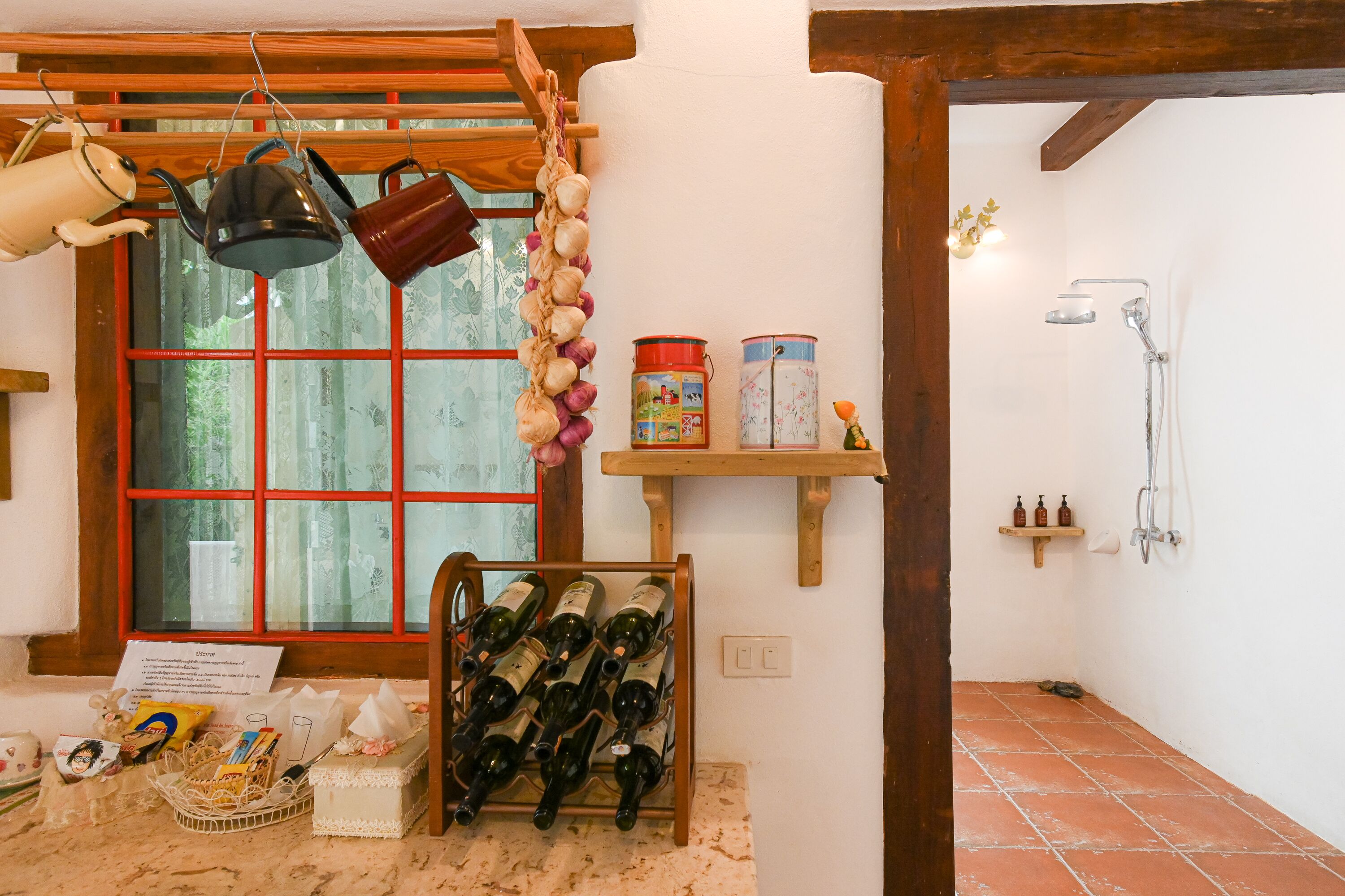 Un baño rústico con un estante de madera que contiene botellas, un colgador de ollas y una zona de ducha.