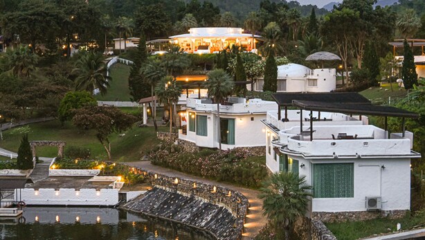 A resort with multiple buildings, a swimming pool, and lush greenery. - Swiss Valley Hip Resort (Suan Phueng)