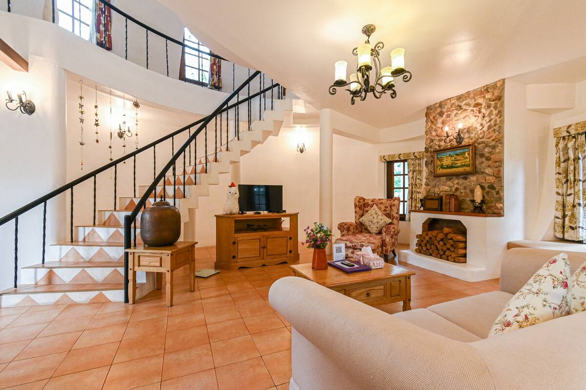A spacious living area with a staircase, a fireplace, and a cozy seating arrangement.
