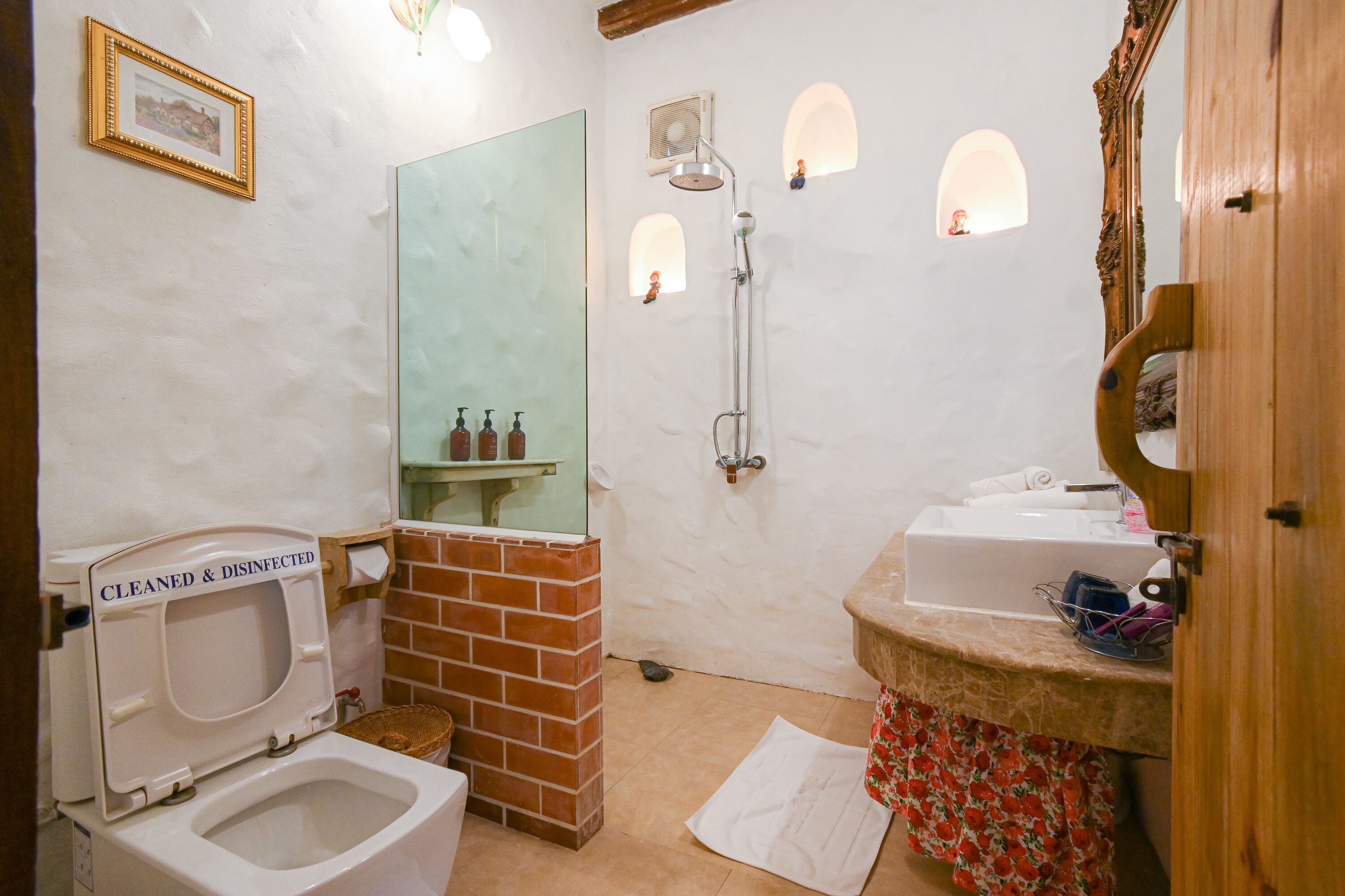 A bathroom with a toilet, a shower, a sink, and a mirror.