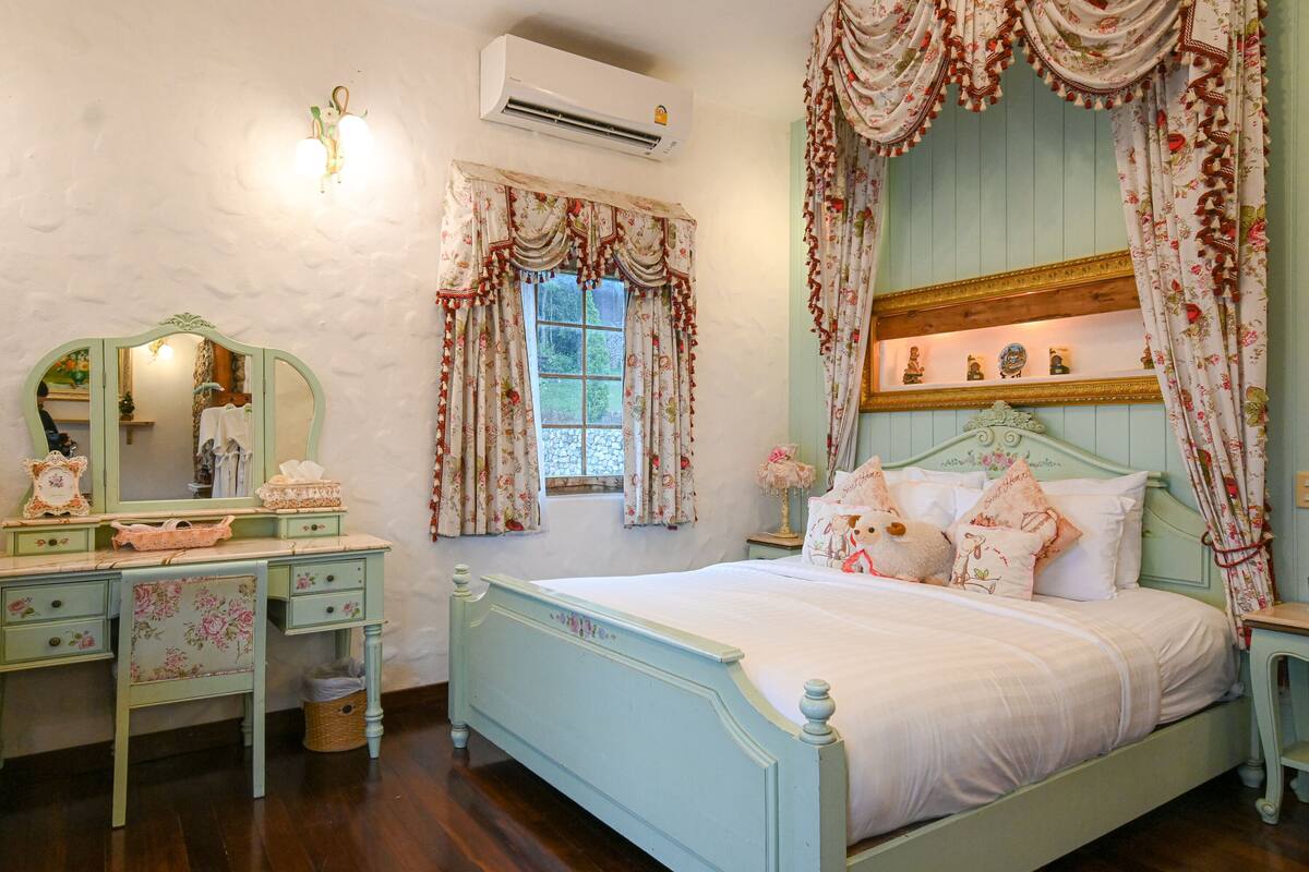 A bedroom with a bed, dresser, mirror, and window with curtains.