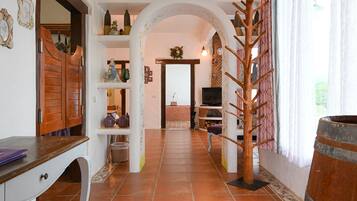A hallway with a wooden door, shelves with decorative items, a brick wall, and a wooden rack with hooks.