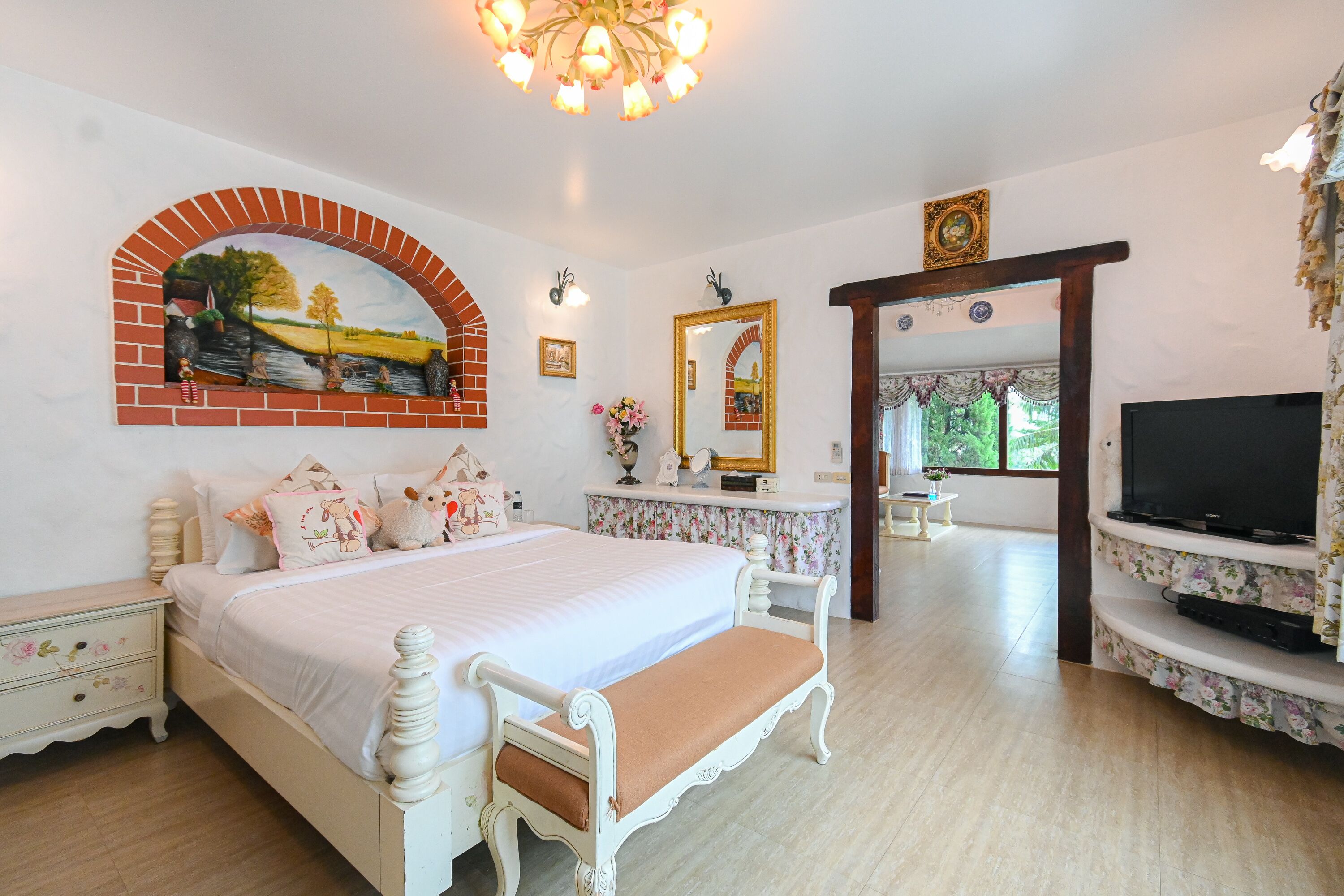 Un dormitorio con una cama, un televisor, un espejo y un cuadro en la pared.