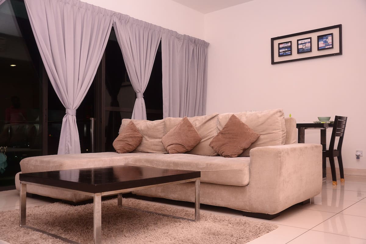 A living room with a beige sofa, a dark coffee table, and a white rug.