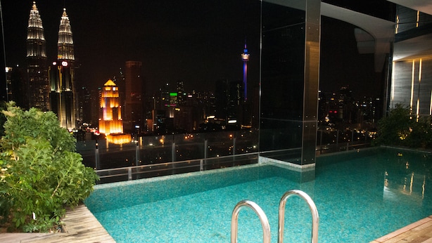 A rooftop pool with a city view, including the Petronas Towers and a lit tower. - Apartment at Setia Sky Residences (Kuala Lumpur)