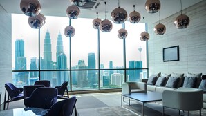 A modern office space with a city view, featuring a white couch, blue chairs, and a glass table. - Apartment at Setia Sky Residences (Kuala Lumpur)