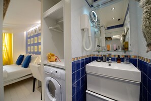 Une chambre d’hôtel équipée d’un lit, d’une machine à laver, d’un lavabo et d’un miroir.