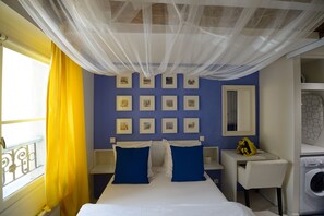 Une chambre à coucher avec un lit, un bureau, un lave-linge et une fenêtre avec des rideaux jaunes.