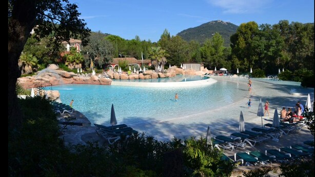 Área de piscina do resort com várias piscinas, espreguiçadeiras e guarda-sóis.