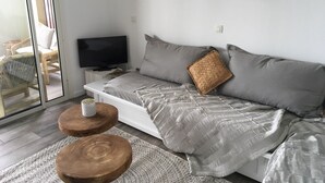 Quarto moderno com uma cama, uma televisão e duas mesinhas de cabeceira de madeira.