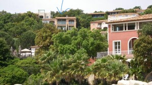 Uma área residencial em um morro com vários edifícios, incluindo um prédio vermelho notável com varanda.