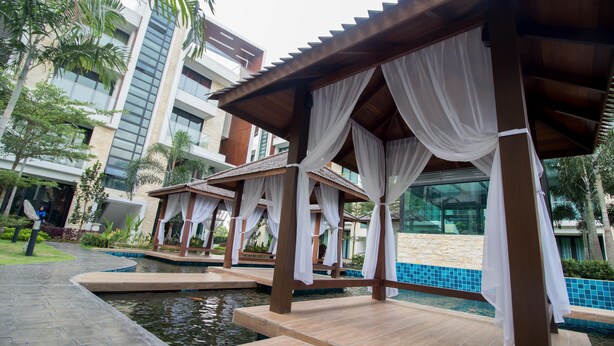 A resort with outdoor seating areas, a pool, and modern buildings in the background. - Tropical Villa Service Suite (Seri Kembangan)