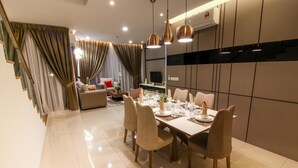 A modern dining area with a long table set for six, surrounded by six chairs. - Tropical Villa Service Suite (Seri Kembangan)