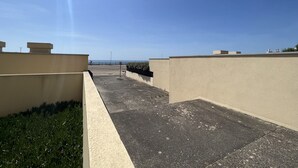 A rooftop terrace with a clear view of the sea, surrounded by beige walls and a small patch of grass. - Studio Amiantis by Agence Bru - 2041 (Lacanau)
