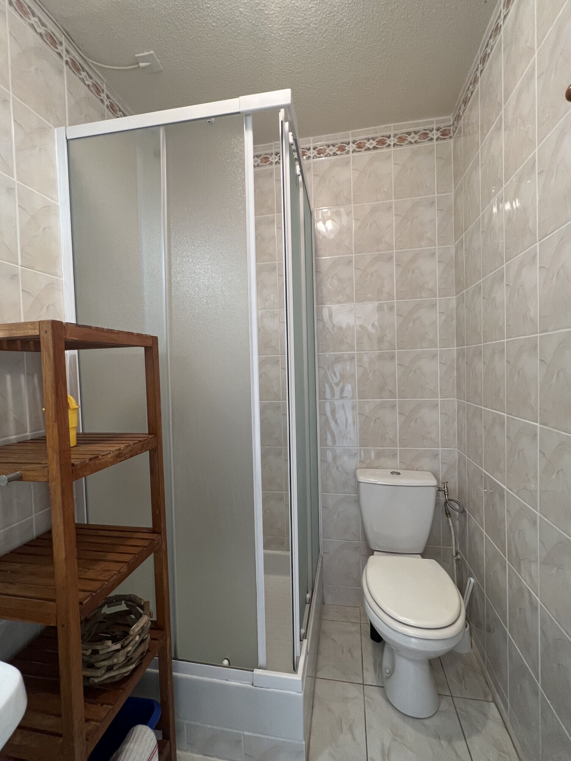 Een badkamer met douchecabine, toilet en houten planken.