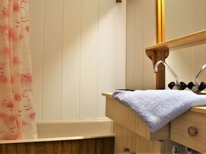 A bathroom with a wooden vanity, a sink with a towel, and a bathtub.