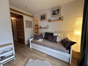 A cozy room with a white sofa, decorative pillows, a small rug, and a lamp. - Ski-In/Ski-Out Studio with Pool, Tennis, and Pet-Friendly in Risoul (Risoul)