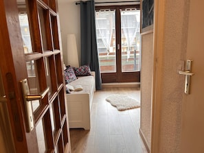 A bedroom with a bed, a window with curtains, a door, and a view of a balcony with a railing.