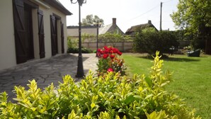 A garden with a stone pathway leading to a building with dark shutters.