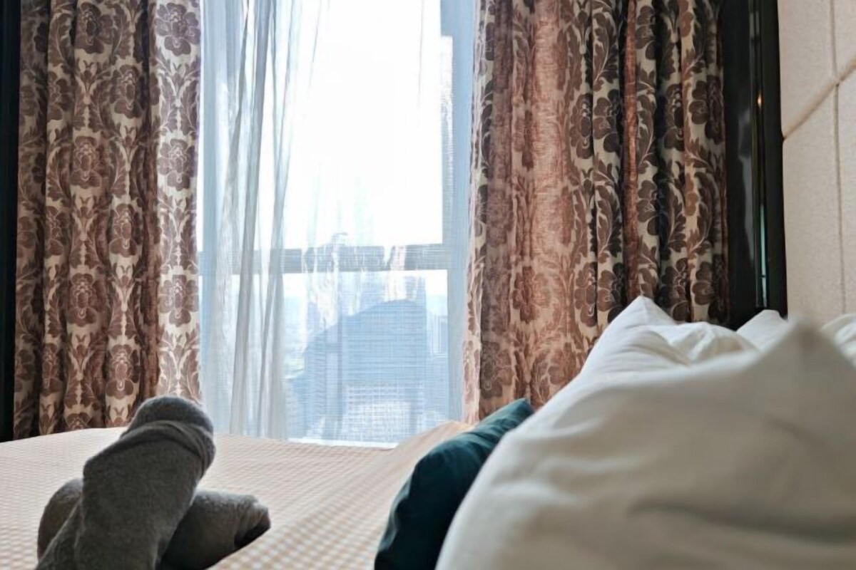 Une chambre d’hôtel avec un lit, une fenêtre avec des rideaux et une vue sur le paysage urbain.