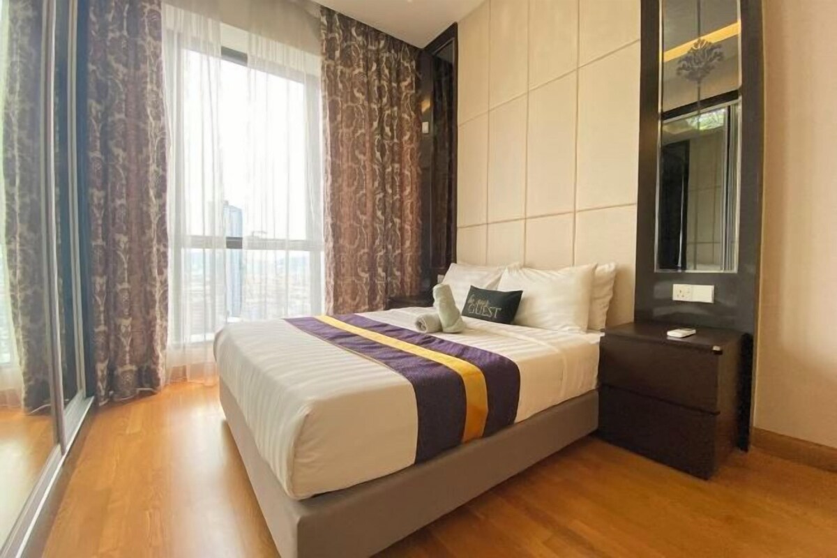 Une chambre d’hôtel avec un grand lit, une table de chevet, un miroir et une fenêtre avec des rideaux.