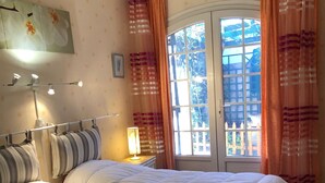 Un dormitorio con una cama grande, una mesita de noche con lámpara y una ventana con cortinas.