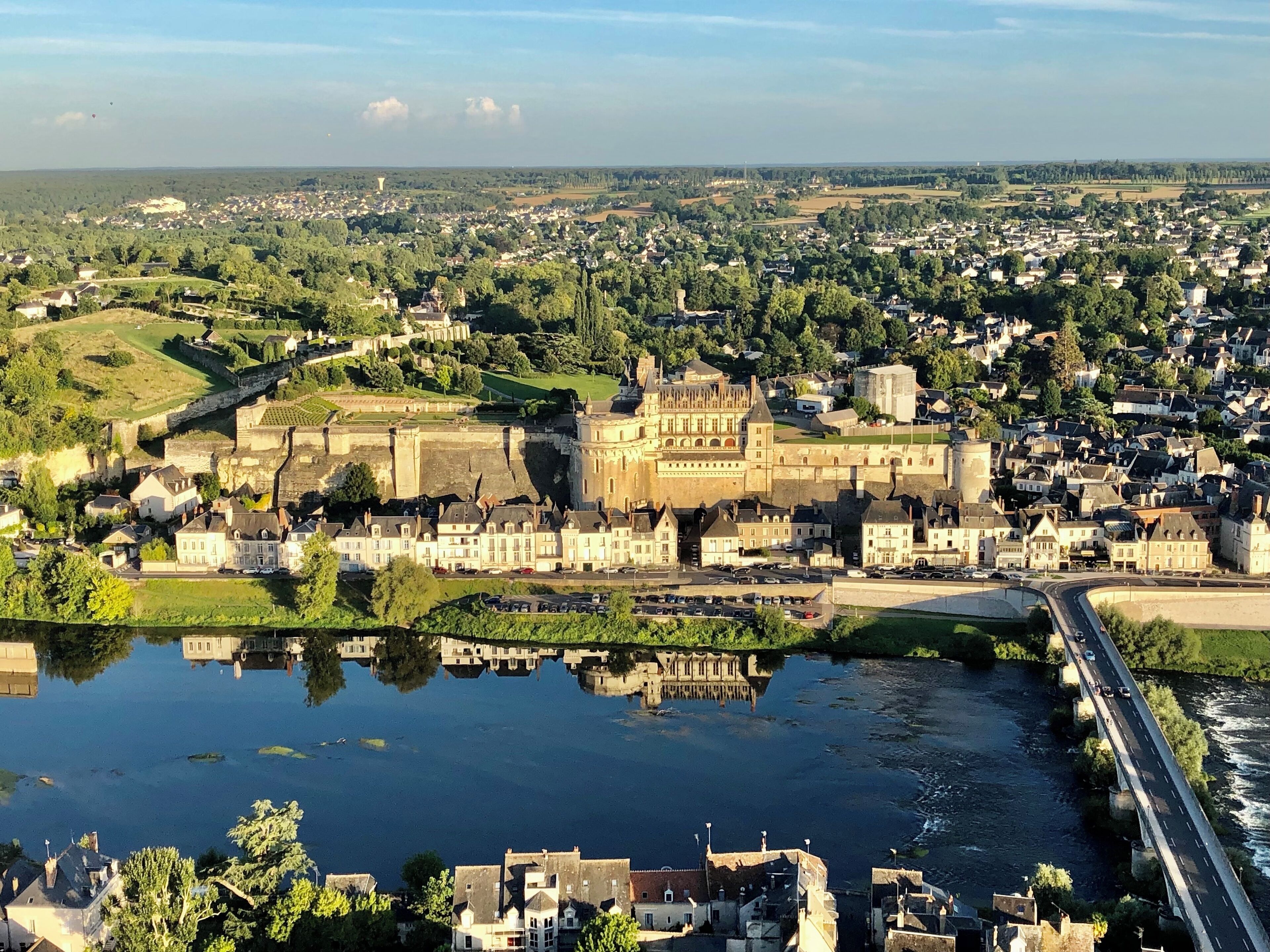 Een historisch kasteel omringd door een stad, met een rivier op de voorgrond.