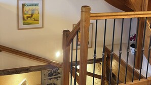 Una escala de fusta amb barana metàl·lica, un quadre amb una imatge de Chambord i una planta en test amb al arribar.