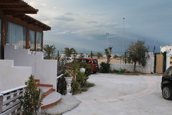 A residential area with a house, a red car, and a clear view of the beach.