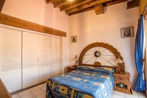 A bedroom with a bed, a nightstand, a wooden headboard, a wardrobe, and a wall-mounted picture.