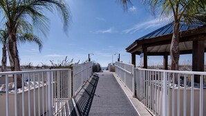 A pathway flanked by white metal railings, leading to a covered structure with a sloped roof.