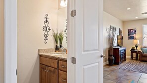 A well-lit bathroom with a wooden vanity, a large mirror, and decorative wall art. - Canyon Oasis - 4 bed home in Coral Ridge! (Washington)
