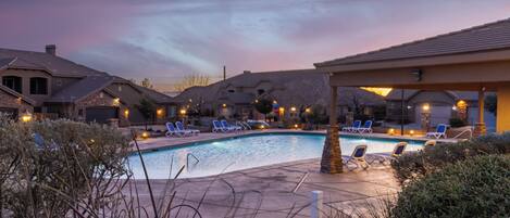 A swimming pool area with lounge chairs and a covered seating area.
