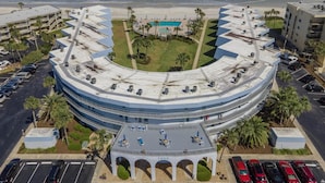 A hotel with a curved rooftop terrace, a swimming pool, and a view of the ocean.