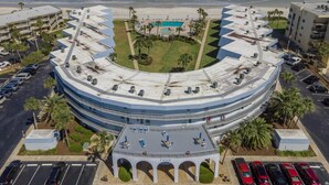 A hotel with a curved rooftop terrace, a swimming pool, and a view of the ocean.