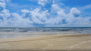 A beach with waves and a clear sky.