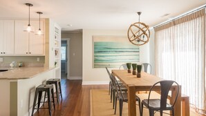 Un comedor con una mesa de madera, sillas y un cuadro grande en la pared.