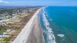 An aerial view of a coastal area with a long sandy beach, residential properties, and a clear blue ocean. - Island Oasis!Golf Cart-Priv.Pool-Bikes-Fenced Yard-Ping Pong-Walk~Beach-Sleep12  (Isle of Palms)