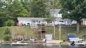 Ein Haus am Seeufer mit Bootsanleger, einem kleinen Boot und einer Veranda.