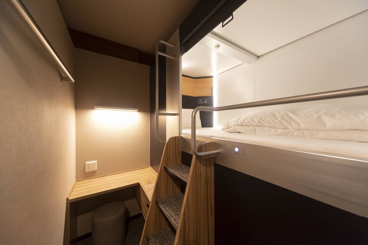 Un compartiment de train compact, équipé d’un lit superposé, d’un petit bureau et d’un espace de rangement intégré.
