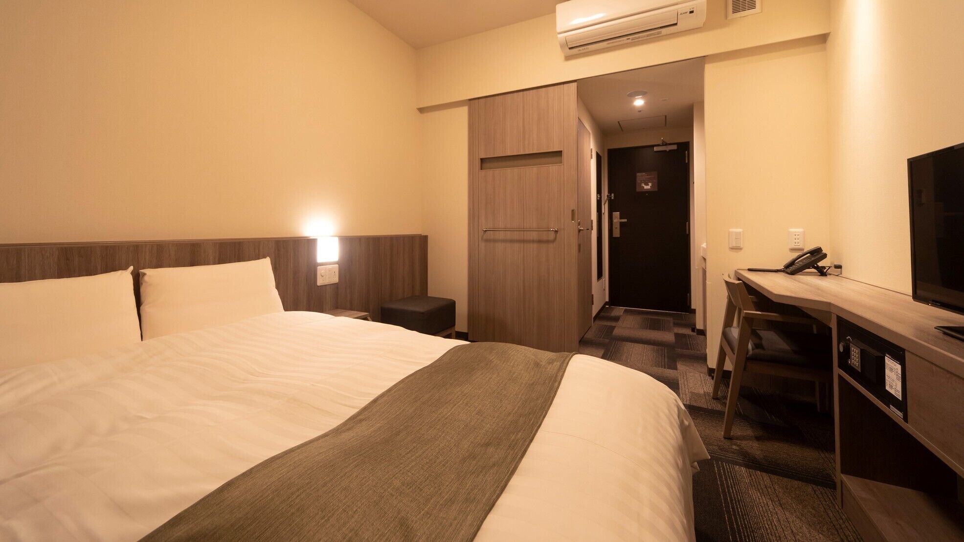 Una habitación de hotel con una cama grande, mesitas de noche, escritorio y televisor.