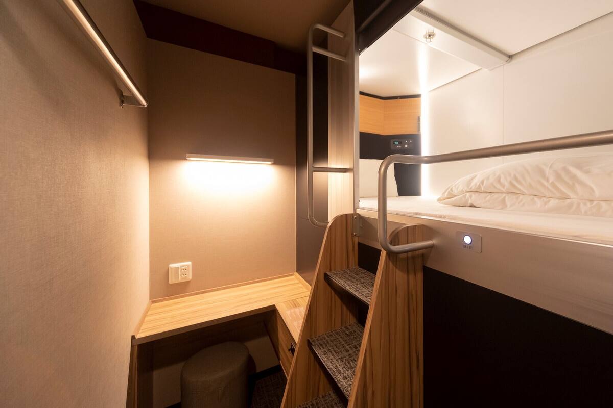 Une petite pièce comprenant un lit superposé, un bureau et une petite chaise.