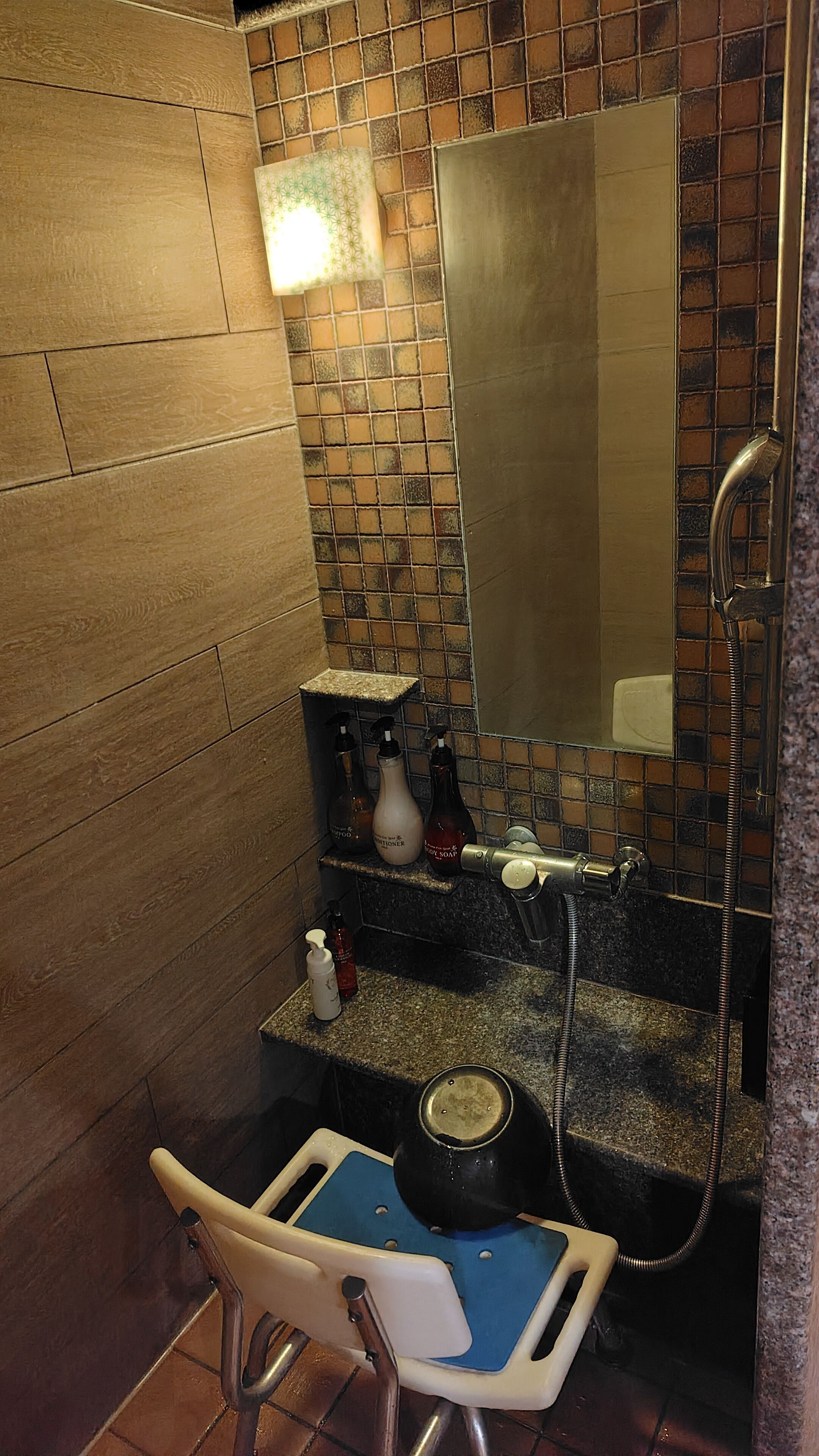 A bathroom with a wooden floor, a tiled backsplash, a sink with a mirror, and a shower area.