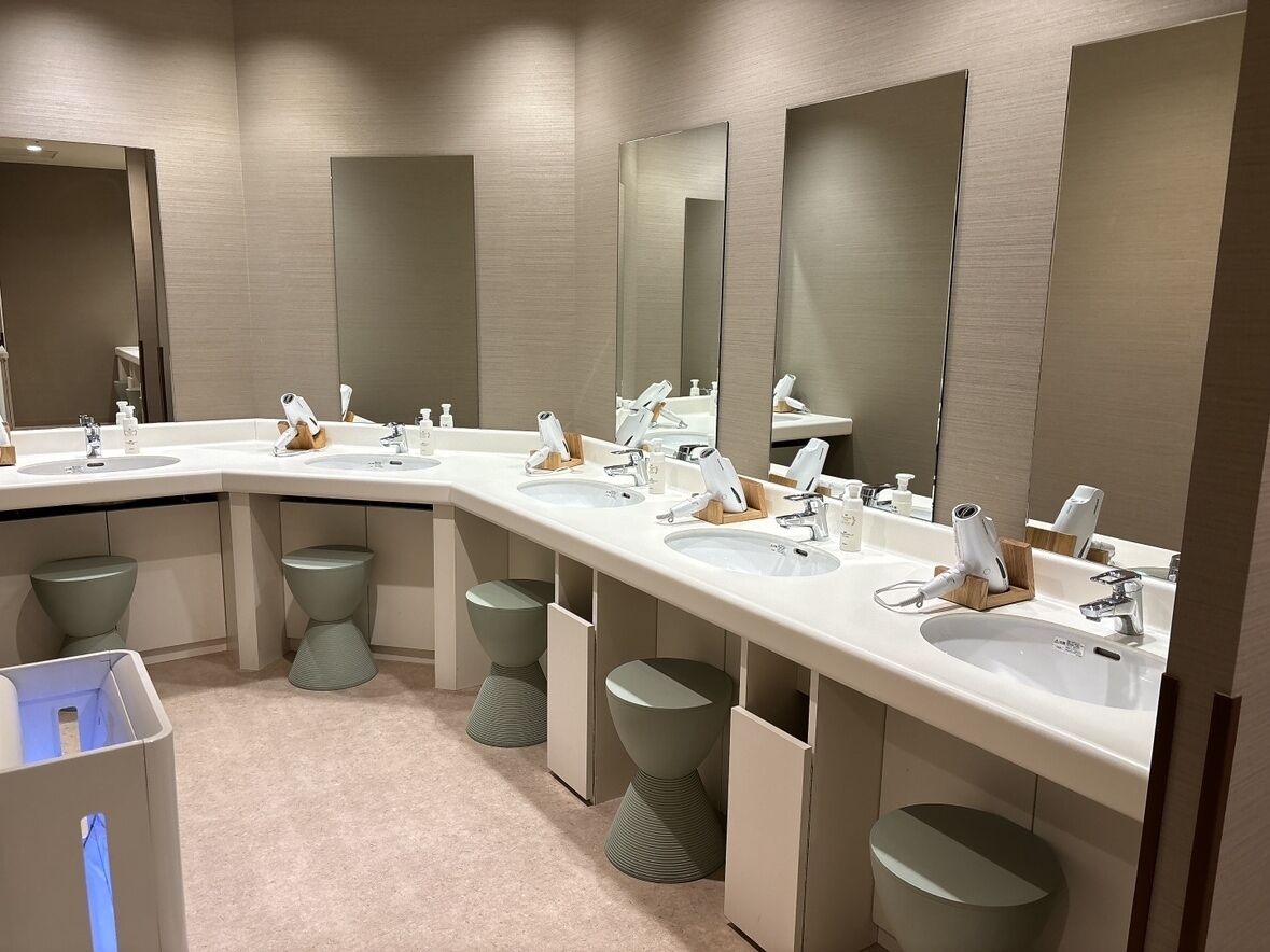 A modern bathroom with multiple sinks, mirrors, and stools.
