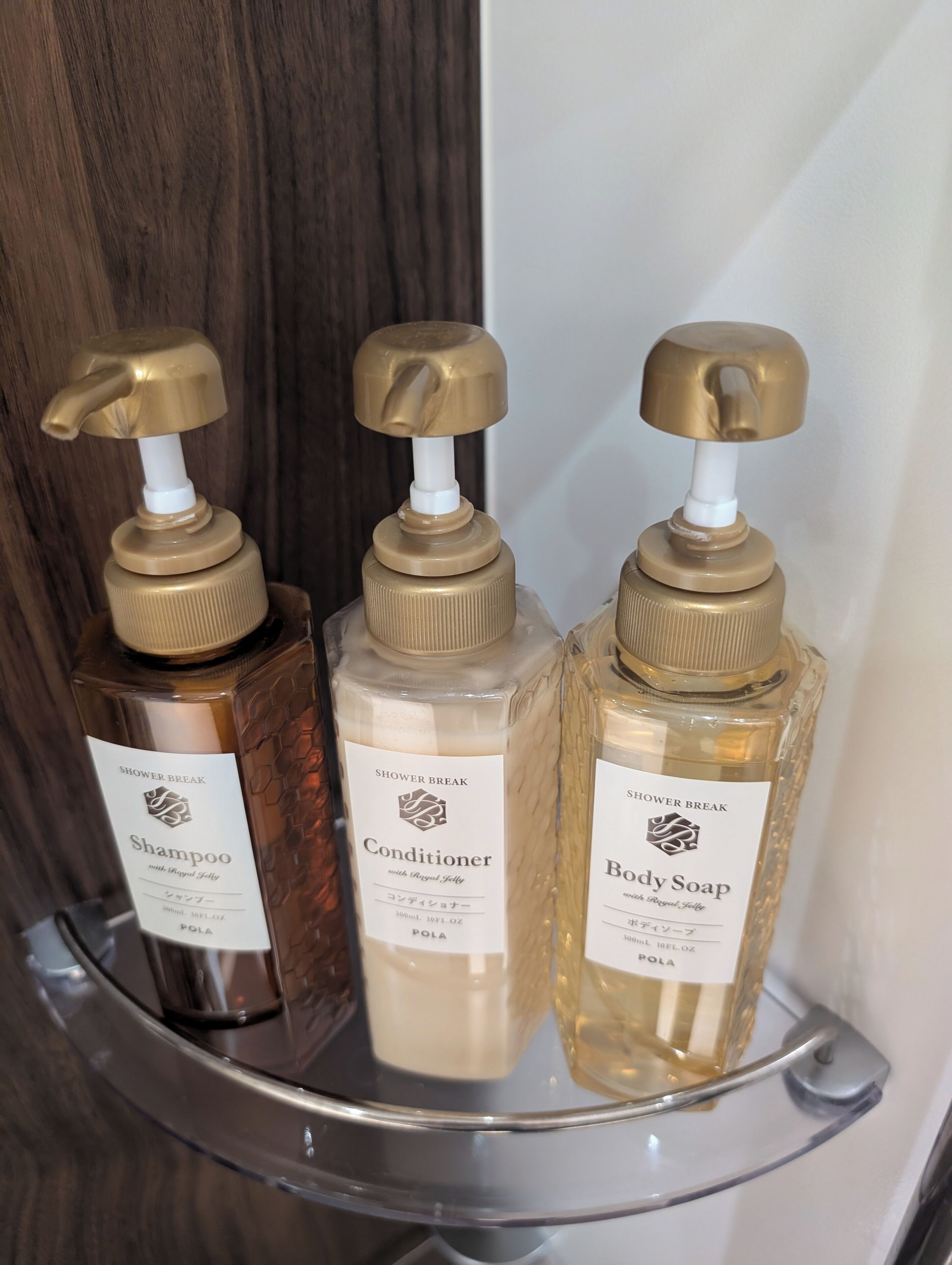Trois bouteilles de produits pour la douche, posées sur une étagère.