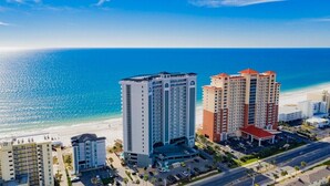 A high-rise hotel with multiple floors, a parking area, and a view of the beach and ocean. - Seawind 405 | Gorgeous updates! Perfect beach view and walk to dine, shop, more! (Gulf Shores)