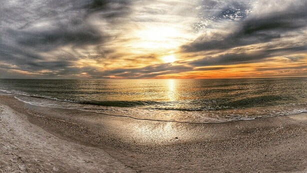 A beach with a sunset over the ocean.