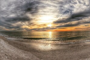 Ein Strand mit Sonnenuntergang über dem Meer.